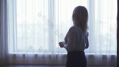 优雅的女孩站窗口饮料咖啡